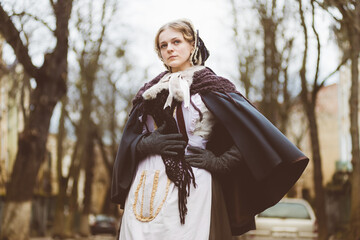 Nineteenth-century woman, elegantly dressed, walks through the courtyard of a castle.
