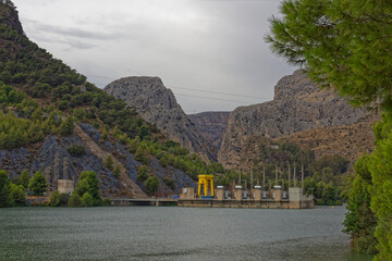 The Industrial Buildings and Pylons of the Caminito del Rey Hydro electric Dam in the waters of the lake at the bottom of the Gorge.