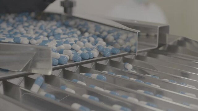 Drug Production. Blue and white pills. Pharmaceutical machinery for medicine production Pills shot in V-Log