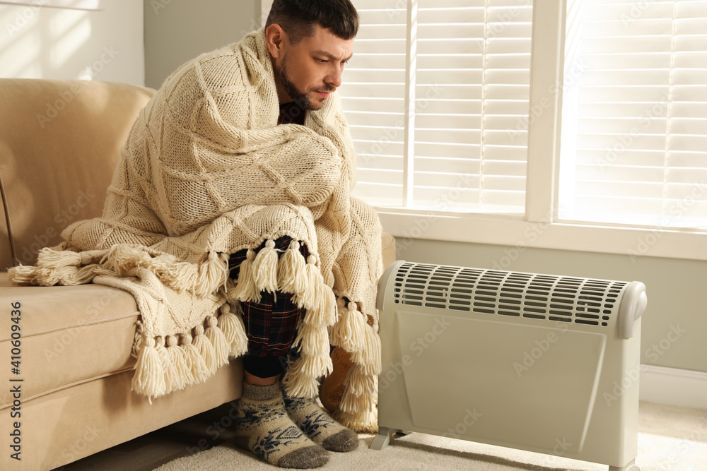 Sticker man warming hands near electric heater at home