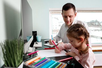 daughter draws with father sitting at the table