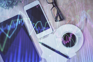 Double exposure of forex chart hologram over desktop with phone. Top view. Mobile trade platform...