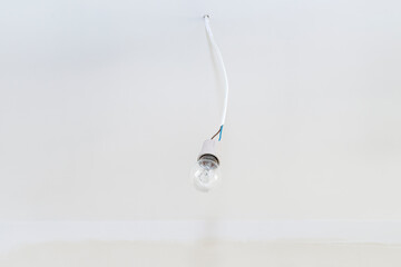 Light bulb hanging on a cable protruding from the wall with a ceramic tip.