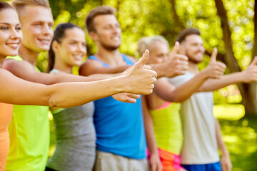 fitness, sport, friendship and healthy lifestyle concept - group of happy teenage friends showing thumbs up outdoors