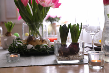 Beautiful Easter table setting with burning candles indoors