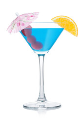 Blue lagoon cocktail in martini glass with orange slice and sweet cherry with umbrella on white.