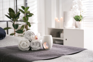 Fototapeta na wymiar Towels, aroma lamp and orchid flower on couch in spa salon