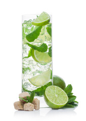 Highball glass of Mojito summer alcoholic cocktail with ice cubes mint and lime on white with cane sugar and raw lime