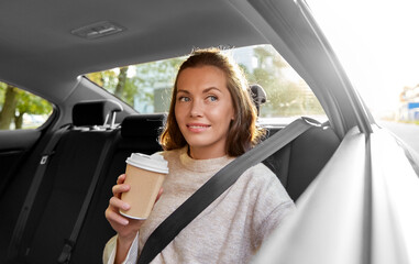 transport, vehicle and people concept - happy smiling woman or female passenger drinking takeaway coffee in taxi car