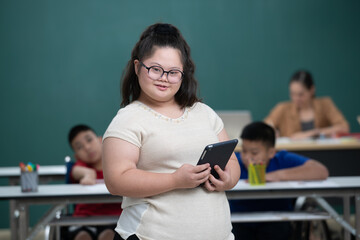 Portrait of young down syndrome girl holding tablet computer in hand with happiness and...