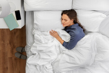 people, relax and comfort concept - young woman sleeping in bed at home