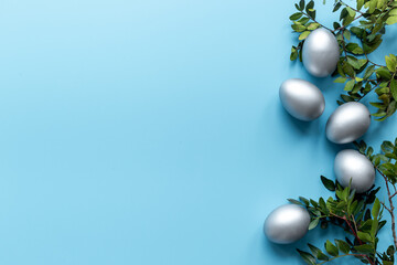 Naklejka na ściany i meble Silver Easter eggs on blue background. Top view decoration