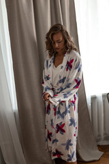 Beautiful and tanned girl in a bathrobe in a home interior