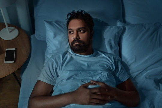 Sleeping, Insomnia And People Concept - Speelpess Indian Man Lying In Bed At Home At Night