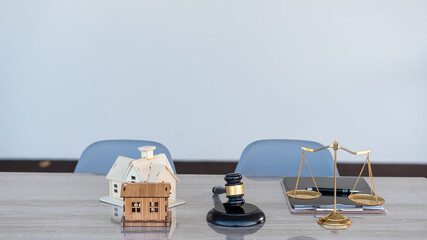 Lawyer hammer and scales with home design on desk and tablet in office