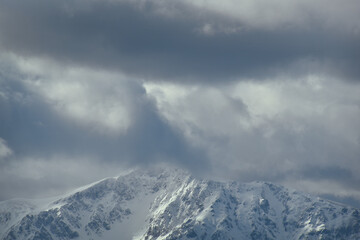 Fototapeta na wymiar Schneebedeckter Berg mit dramatischen Wolken