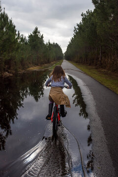cute little girl riding on flooded bike path after storm