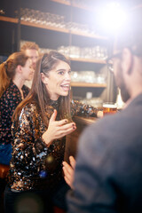 Group of cheerful friends standing near bar counter, drinking beer and chatting.