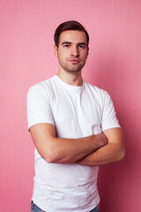 Fototapeta premium young caucasian guy in white t-shirt posing cheerful on pink background, lifestyle people concept