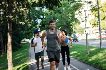Obraz premium Group of young people in sports clothing running in city park.