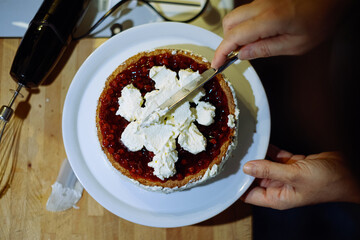 person prepairing cake with whipped cream on table