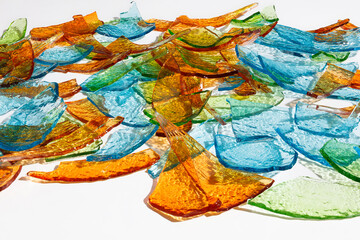 Background of broken fragments of colored multicolored glass with blurred reflections on white background .