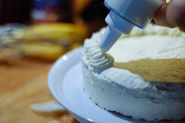 person prepairing cake with whipped cream on table
