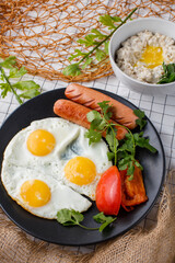 English breakfast. fried eggs with sausages and tomatoes and oatmeal with butter