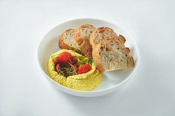 Classical oriental dishe - hummus of chickpeas with sun-dried tomatoes with croutons in a white plate on a white background