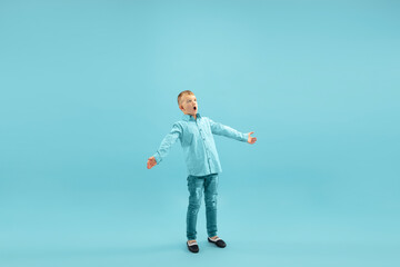 Astonished. Childhood and dream about big and famous future. Pretty little boy isolated on blue studio background. Childhood, dreams, imagination, education, facial expression, emotions concept.