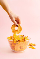 Woman's hand taking pineapple ring from a bowl with fruit jerky