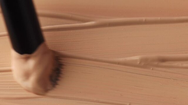 beige smear of tonal foundation cream background close up, smudge with a brush, beautiful pastel texture, cosmetic product for make up