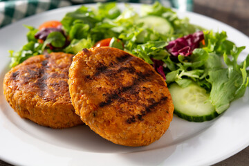 Delicious healthy chickpea burger and salad on wooden table