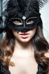 Beautiful and young woman posing in sexy lingerie and Venetian mask 
