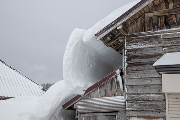 屋根雪の重みでで倒壊しそうな家	