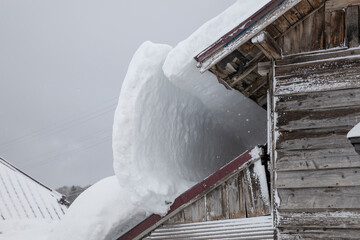 屋根雪の重みでで倒壊しそうな家	