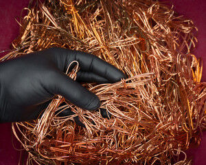 gloved hand holds scrap copper wire for recycling