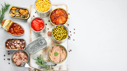 Various canned vegetables, fish and peas in aluminum cans on light gray background.