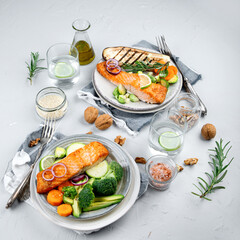 Two portions of homemade fresh salmon with vegetables on a light background.
