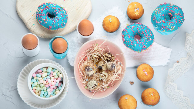 Easter composition with eggs and colorful sweets on light gray background.