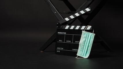 BLACK director chair with Clapperboard or movie Clapper board and face mask on black background.it use in video production or movie and cinema industry.