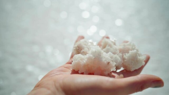 slow motion First person view woman hand holding crystallized salt natural mineral formation at beautiful landscape of Salt Flats with highlight sunlight