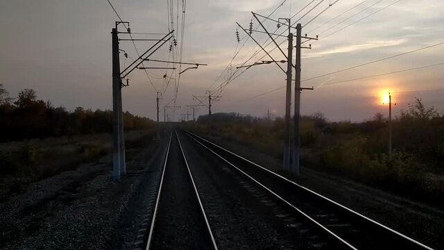 The view from the train driver's cab at sunset, the rails go into the distance. Indian summer - yellow leaves of trees. Train travel concept.