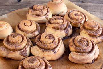 Freshly baked cinnamon buns with spices and cocoa filling on parchment paper. Sweet Homemade Pastry christmas baking. Close-up. Kanelbule - swedish dessert.