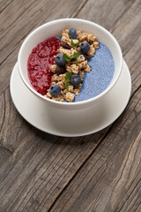 Breakfast smoothie bowl with granola on wooden background