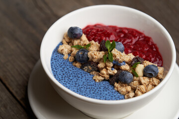 Breakfast smoothie bowl with granola on wooden background