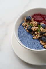 Breakfast smoothie bowl with granola on white background