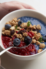 Breakfast smoothie bowl with granola on white background