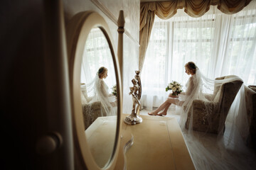 Wedding preparation. Blonde bride sitting in chair in luxury apartments