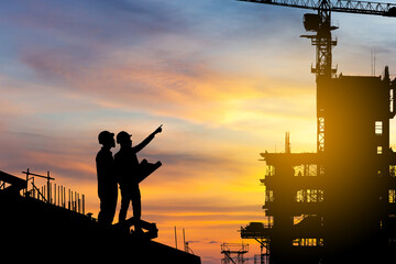 Silhouette of Engineer and worker checking project at building site background, construction site...